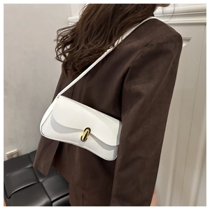 Close-up of a model wearing a white minimalist leather bag with a gold metal clasp