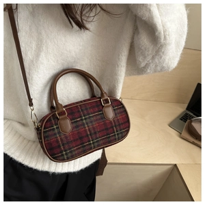 Details der rot-grünen Boston-Tasche mit Karomuster, Lederbesatz und Goldbeschlägen