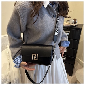 Detail of black leather crossbody bag with geometric silver buckle and woven strap