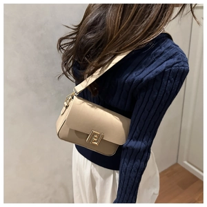 Detail of cream baguette bag with gold F-shaped metal clasp and leather strap