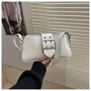 Détail du sac baguette blanc avec grande boucle en métal argenté et œillets sur la sangle