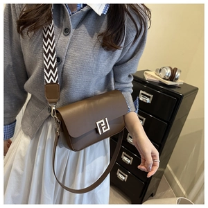 Brown leather crossbody bag detail featuring interchangeable woven and leather straps
