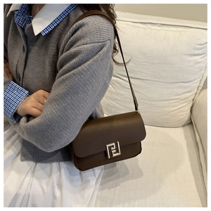 Detail view of brown leather shoulder bag with elegant gold geometric metal buckle