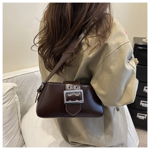 Detail of vintage brown leather underarm bag with silver buckle worn with trench coat