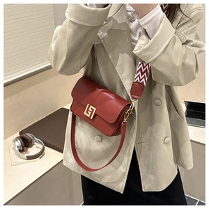 Close-up of retro brown crossbody bag featuring golden geometric clasp and woven strap