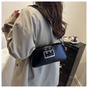 Detailed close-up of matte black leather baguette bag with a decorative silver belt buckle