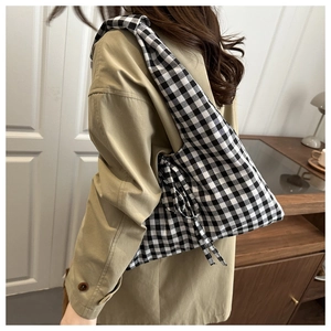 Detail of checkered gingham tote bag featuring decorative tie and textured cotton fabric