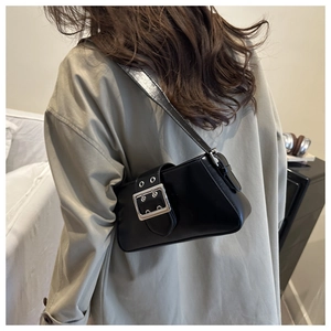 Detail of a black leather underarm bag featuring a large silver buckle decoration