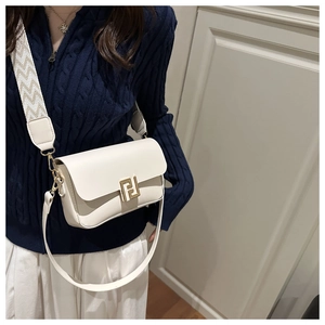 Detail of white leather shoulder bag featuring a wide jacquard strap and gold buckle