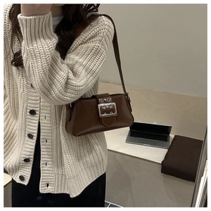 Detail of retro dark brown underarm bag featuring a wide belt and silver metal buckle