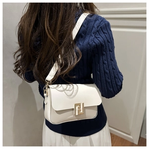 Side view of a beige leather flap bag with gold F buckle worn on a dark blue sweater