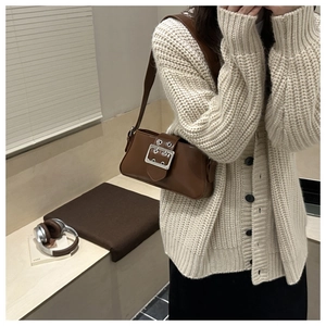Brown faux leather shoulder bag with metallic buckle detail worn by a model