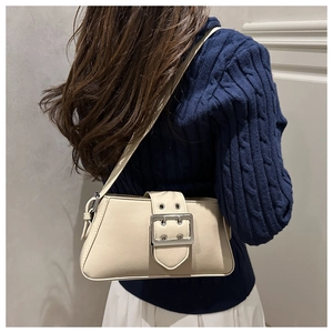 Close-up of beige faux leather shoulder bag featuring a large silver metal buckle on a model