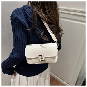 Detail of cream white leather crossbody bag with gold F-letter clasp on navy sweater