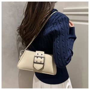 Detail of cream leather shoulder bag featuring silver buckle and metal eyelet accents