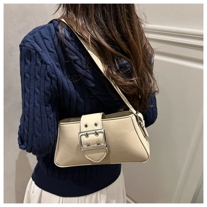 Detail view of beige rectangular shoulder bag with large silver metal buckle and strap