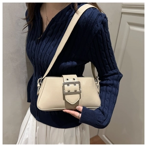 Détail du sac à bandoulière crème avec grande boucle argentée et œillets décoratifs