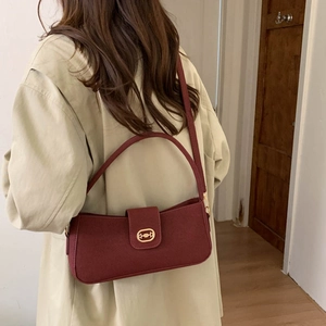 Bolso de hombro burdeos minimalista con hebilla dorada mostrado en una modelo