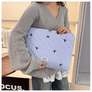 Dettaglio custodia per laptop in nylon azzurro trapuntato con fiocchi neri e cerniera in metallo