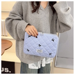 Détail de la pochette matelassée lilas avec broderie nœud noir et double fermeture