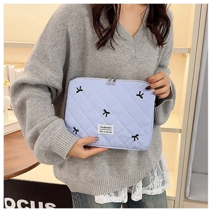 Détail de la pochette matelassée bleu clair avec broderie nœud et fermeture zippée