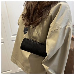 Detail view of black cylindrical crossbody bag with gold zipper and fashion text