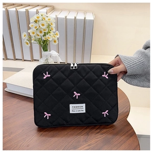 Détail de la housse d'ordinateur matelassée noire avec broderie nœud rose et fermeture