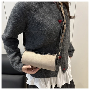 Detail of beige suede barrel bag with black leather trim and jacquard wide strap