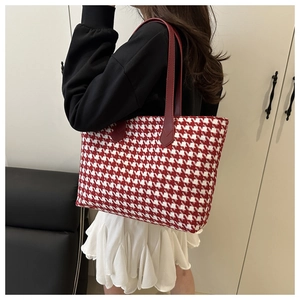 Detail of red and white houndstooth tote bag featuring red leather shoulder straps