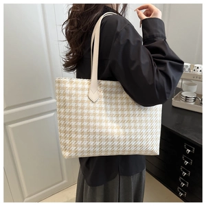 Detail view of houndstooth tote bag on model showing large capacity and textured fabric