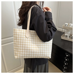 Detail of elegant houndstooth tote bag with leather handles shown in a lifestyle setting