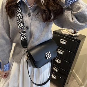 Classic black leather crossbody bag with gold buckle and geometric woven strap