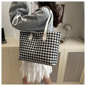 Classic black and white houndstooth tote bag with slim white straps worn by a model
