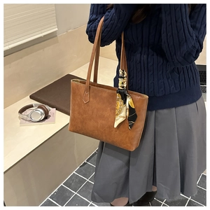 Detail showing vintage brown textured tote bag with elegant silk scarf on handle