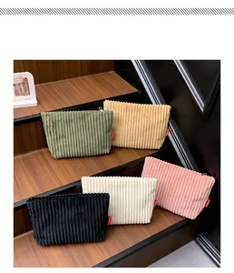 Five corduroy makeup bags in various colors displayed on a wooden step ladder