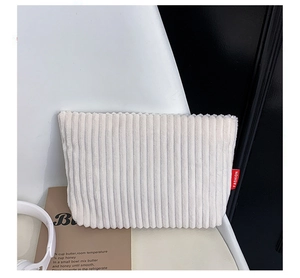 Macro view of cream corduroy envelope bag texture with red Fashion brand label detail