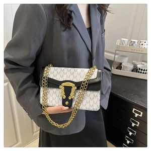 Close-up of vintage flap bag featuring M-letter print and gold embossed lock detail