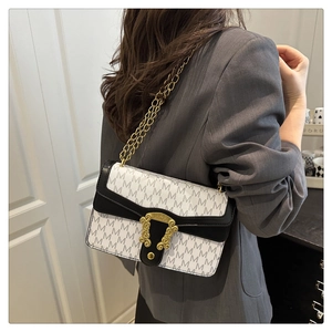 Detailed view of checkered M-pattern shoulder bag with gold chain on grey blazer