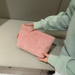 Detailed texture of pink corduroy fabric on a minimalist clutch with a fashion label