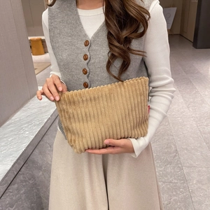 Detail of light brown corduroy handbag showing ribbed texture and red woven brand tag
