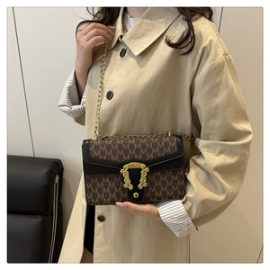 Detailed shot of retro monogram leather bag with gold chain strap on a model
