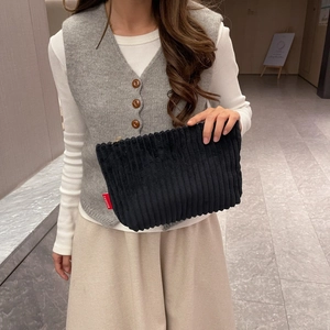 Detailed texture of black corduroy handbag featuring a red FASHION woven label detail