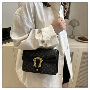 Detail of crossbody bag featuring grey letter patterns and vintage gold metal lock