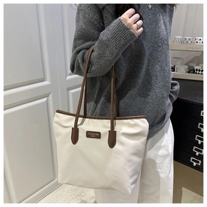 Detailed view of cream-colored Oxford tote bag with brown leather straps for commuting