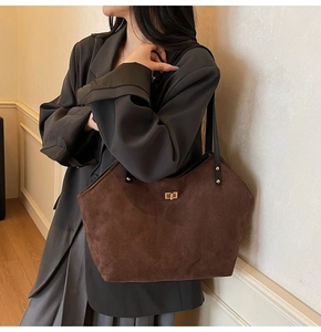 Detail view of coffee-colored quilted suede tote bag featuring a gold twist lock closure