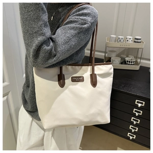 Detailed shoulder view of a large oxford cloth tote bag in cream and brown contrast colors