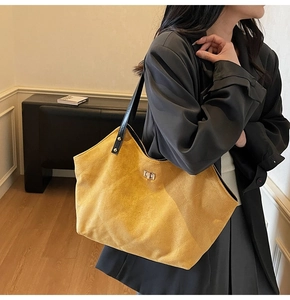 Detail of yellow quilted suede tote with black straps and golden twist lock closure