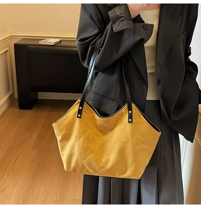 Detail of yellow quilted suede tote bag with metal buckle worn by a model in a blazer