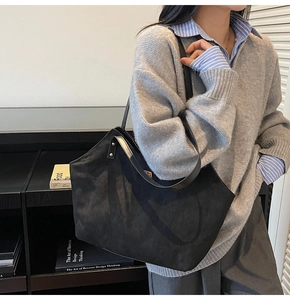 Model wearing a large black matte suede tote bag with reinforced studs for daily commuting