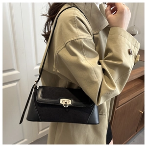 Detail view of a black color-blocked underarm bag with gold ring buckle on model